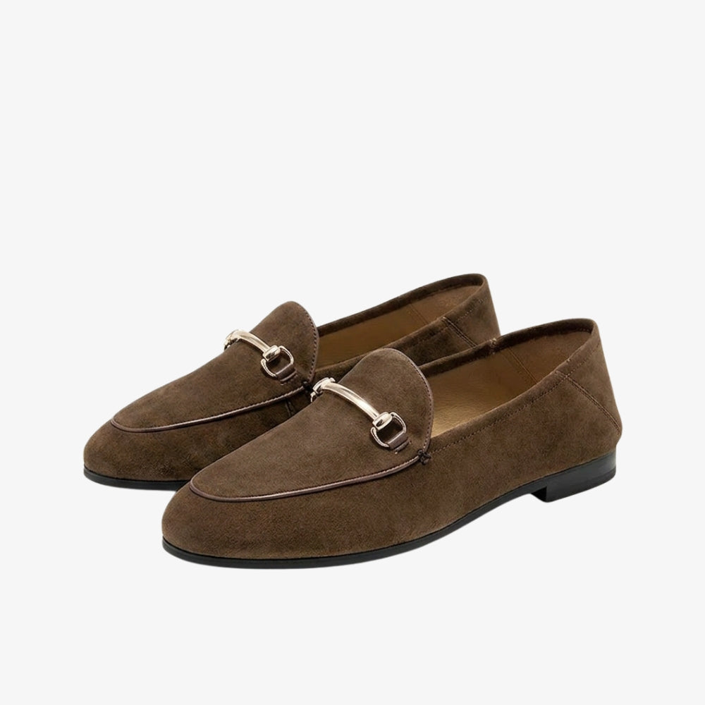 Loafers i äkta brun mocka med metallisk hovbetselsdetalj, mot grå bakgrund