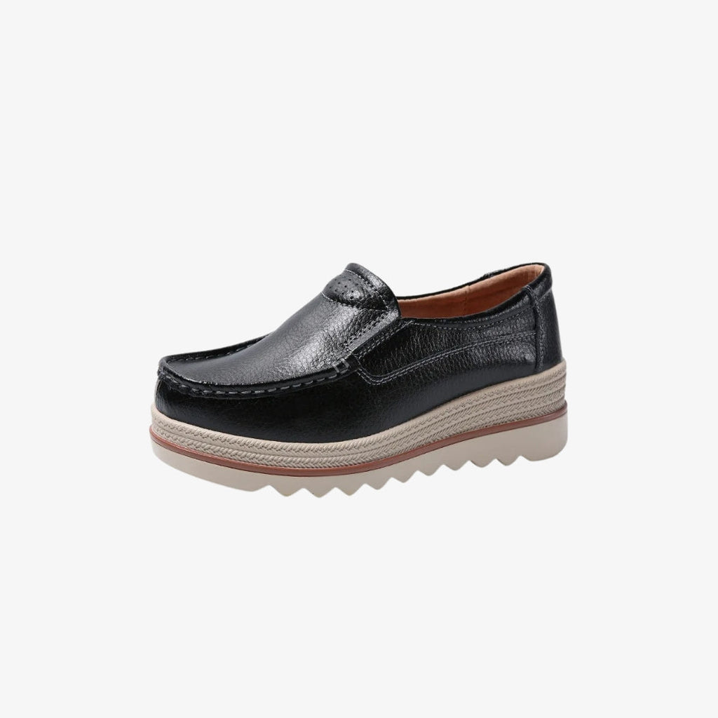 Kilklackade loafers för dam i svart syntetiskt läder, med elegant och tidlös design. Skorna har en tjock beige sula med flätade detaljer och en räfflad botten för bättre grepp. Insidan ger optimal komfort hela dagen.