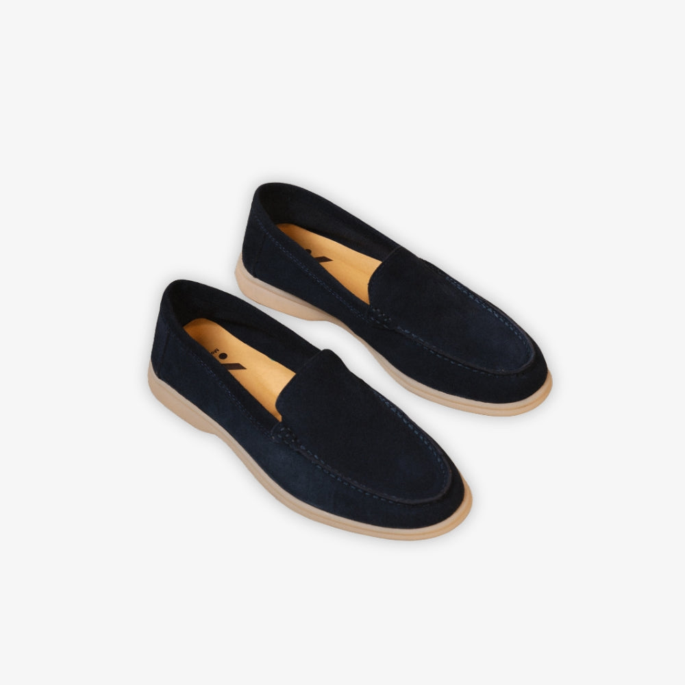 Blå Yacht-loafer på golvet mot beige bakgrund