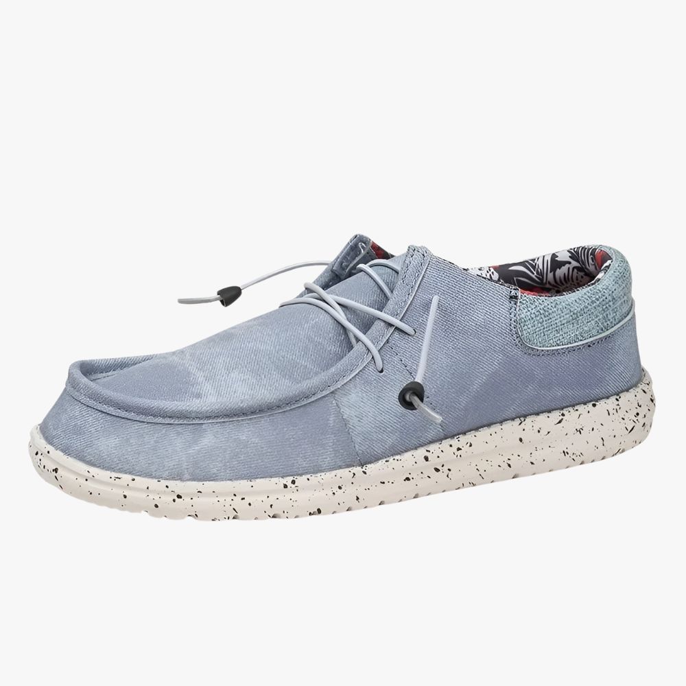 Loafers i blått tyg med vita sulor. Tyget på insidan är blommigt.