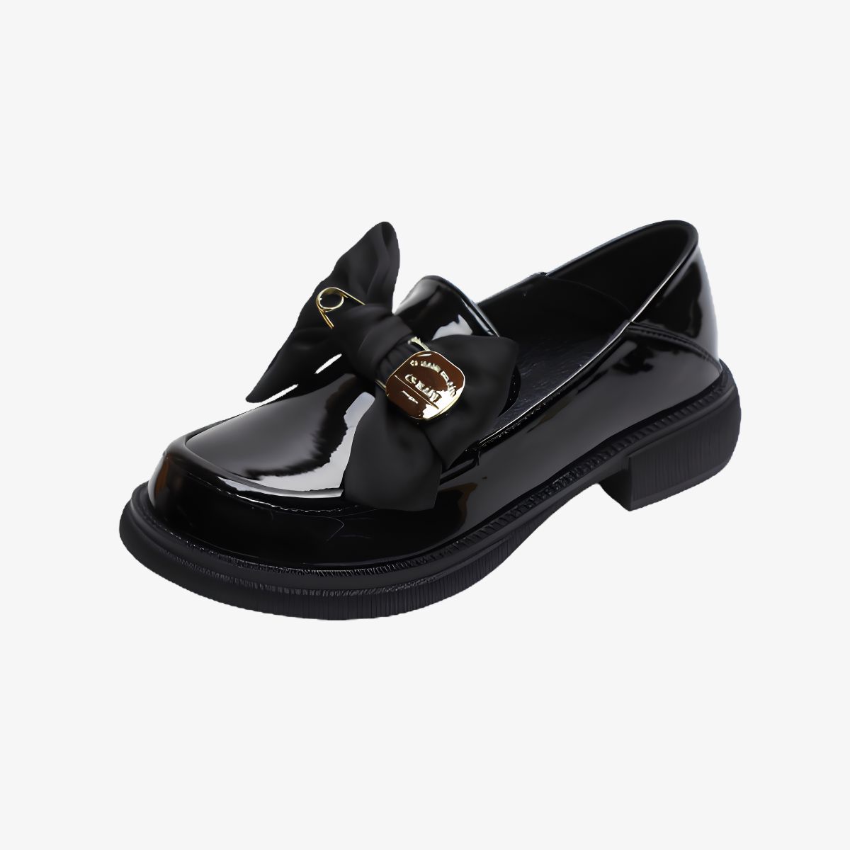Svarta lackloafers med tjock sula, rosett och nål mot mycket ljusgrå bakgrund