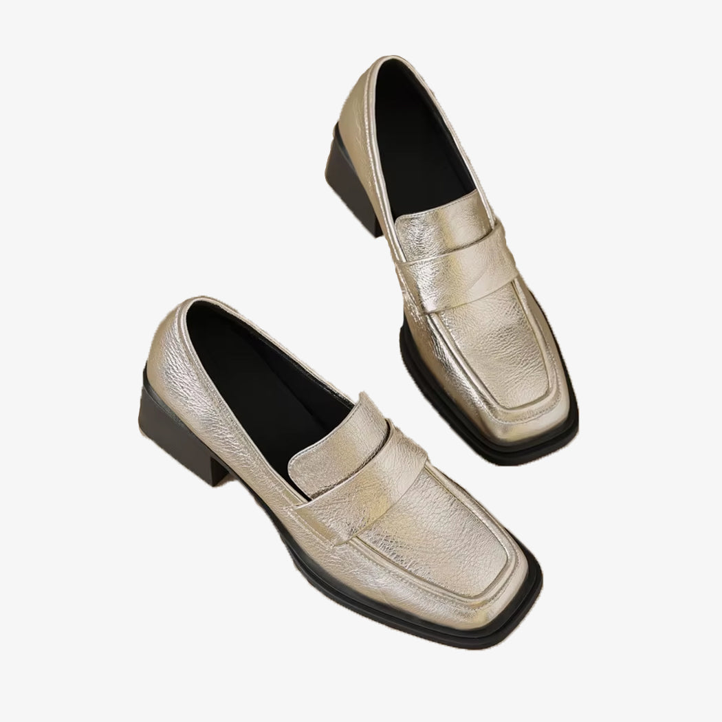 Gyllene loafers med klack för kvinnor på vit bakgrund