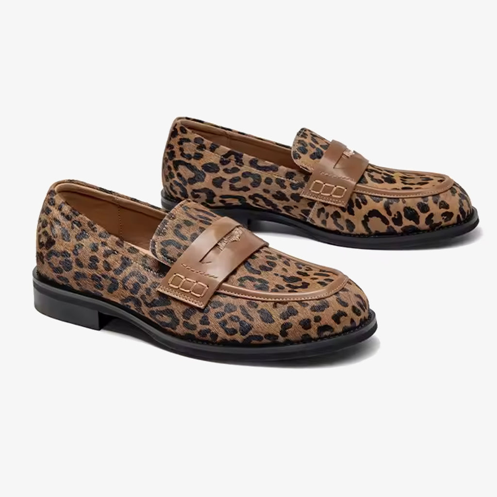 Par loafers i leopardläder med rem över vristen på vit bakgrund