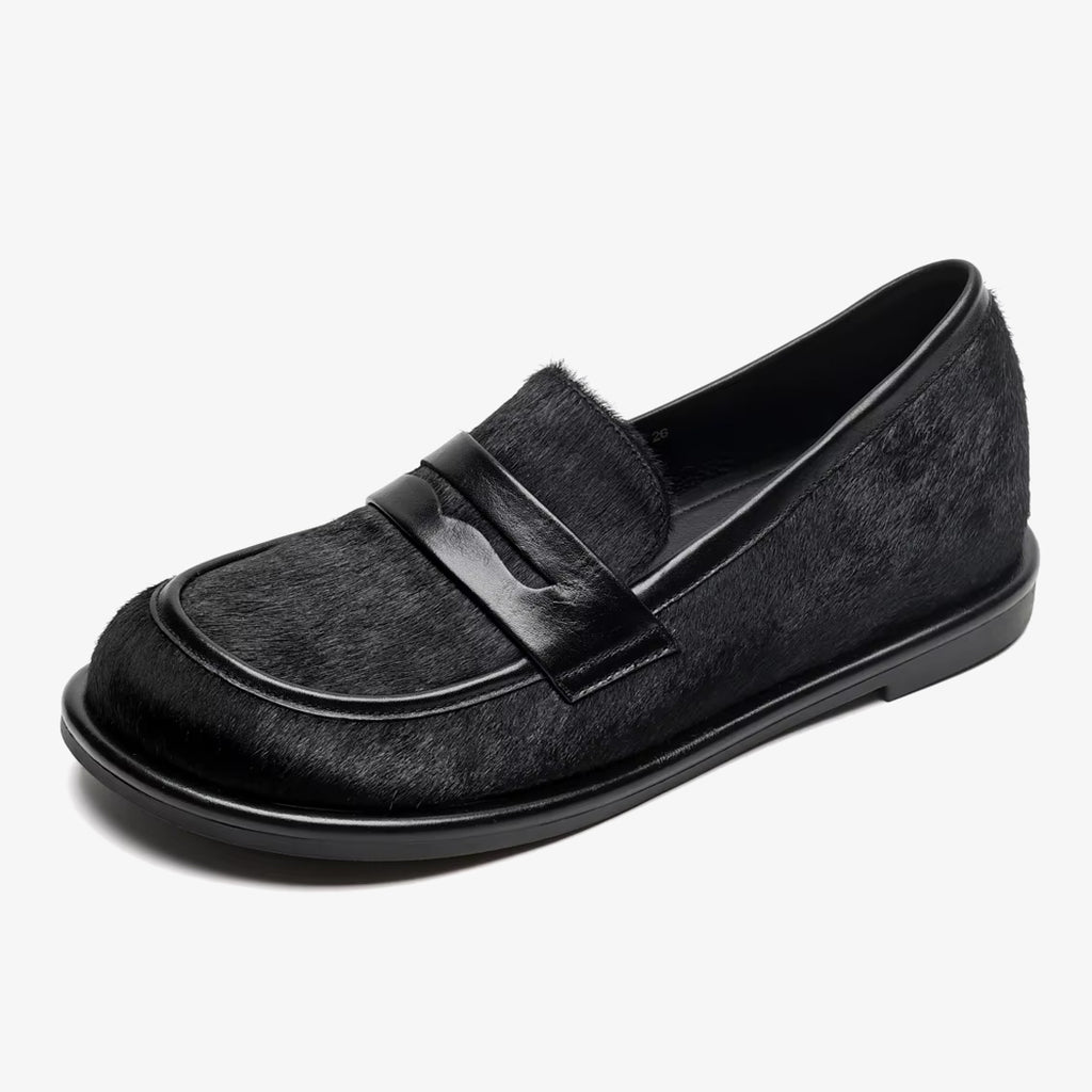 En svart loafer i läder och tagel på vit bakgrund