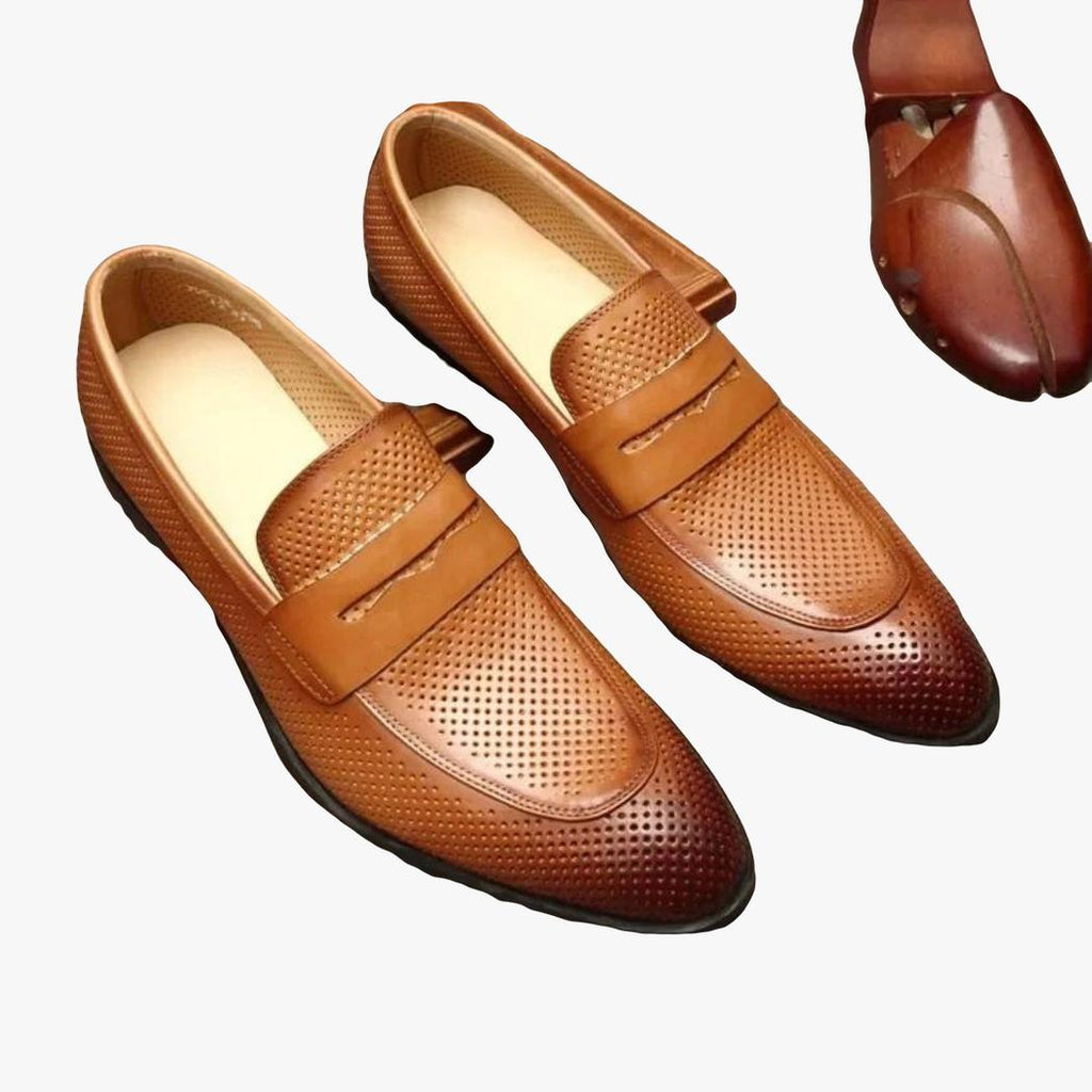 På en grå bakgrund syns ett par bruna loafers med spetsig tå i äkta läder för herr