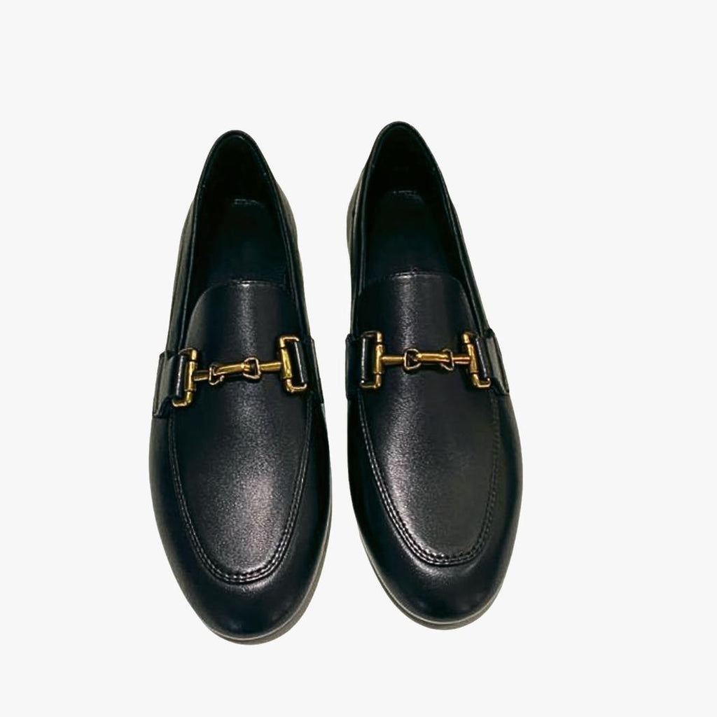 på en vit bakgrund syns ett par svarta loafers för dam i äkta läder