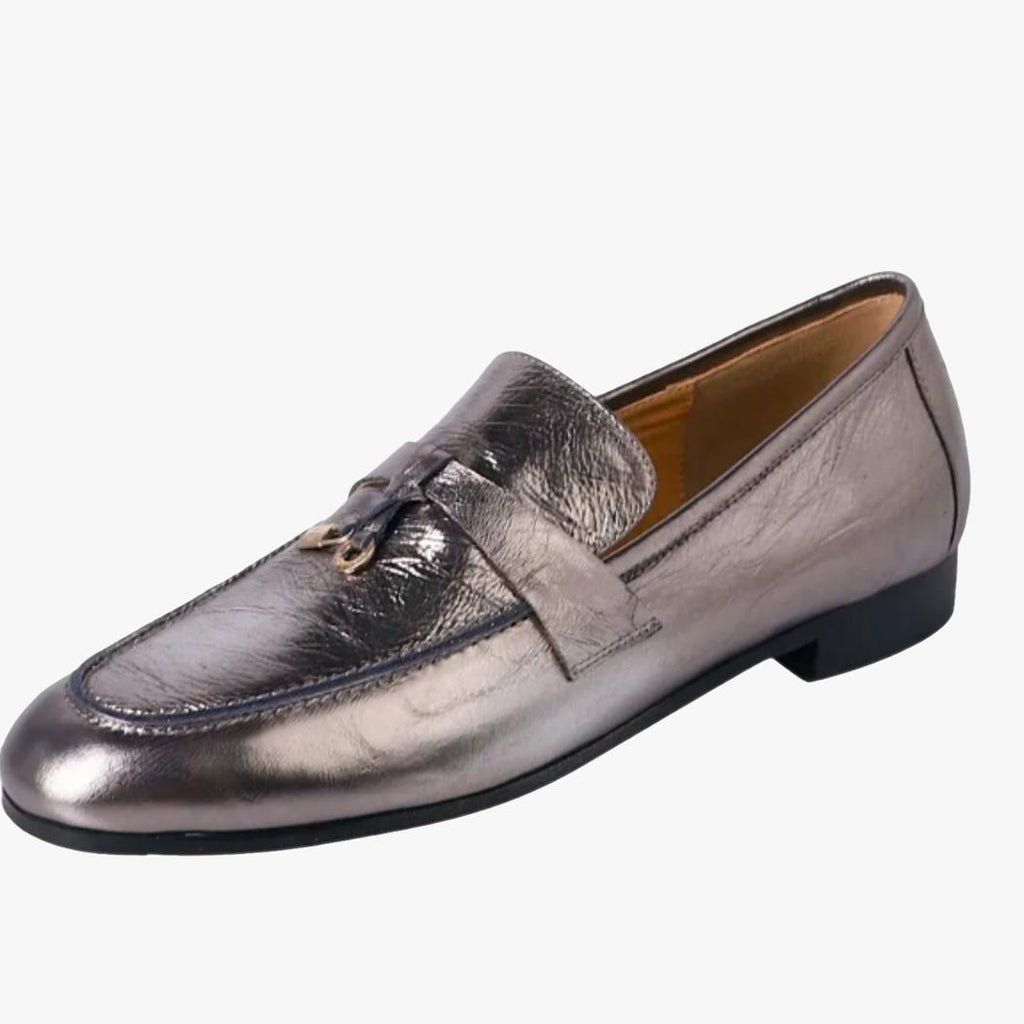 på en vit bakgrund syns en silverfärgad tassel loafer för dam i äkta läder