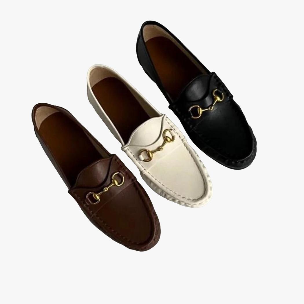 På en ljusgrå bakgrund syns tre mjuka loafers i äkta läder för dam, en vit, en brun och en svart.