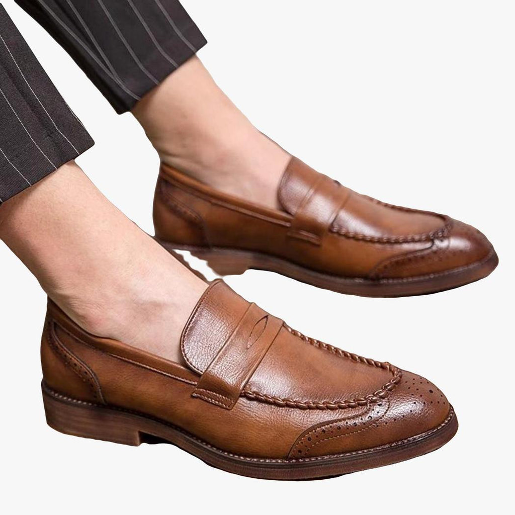 En sittande man syns, med fötterna i bruna loafers