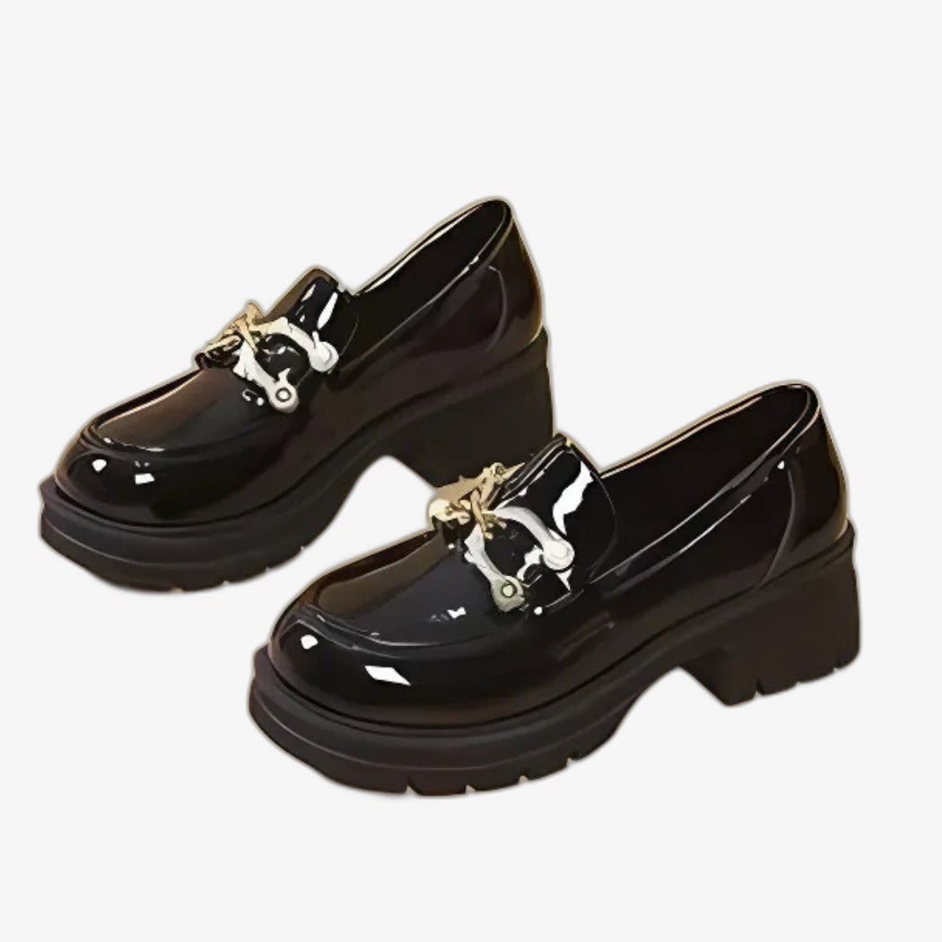 Svarta lackloafers för dam i chic och modern stil. Med grov klack för hållning och god stabilitet och ett elegant silverfärgat metallspänne på ovansidan, som ger den blanka designen en förfinad touch.