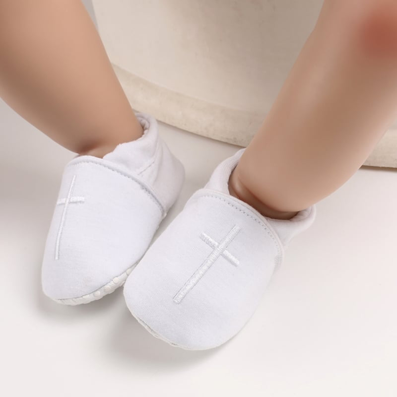 Dopmockasiner i vit bomull med broderat kors på ovansidan