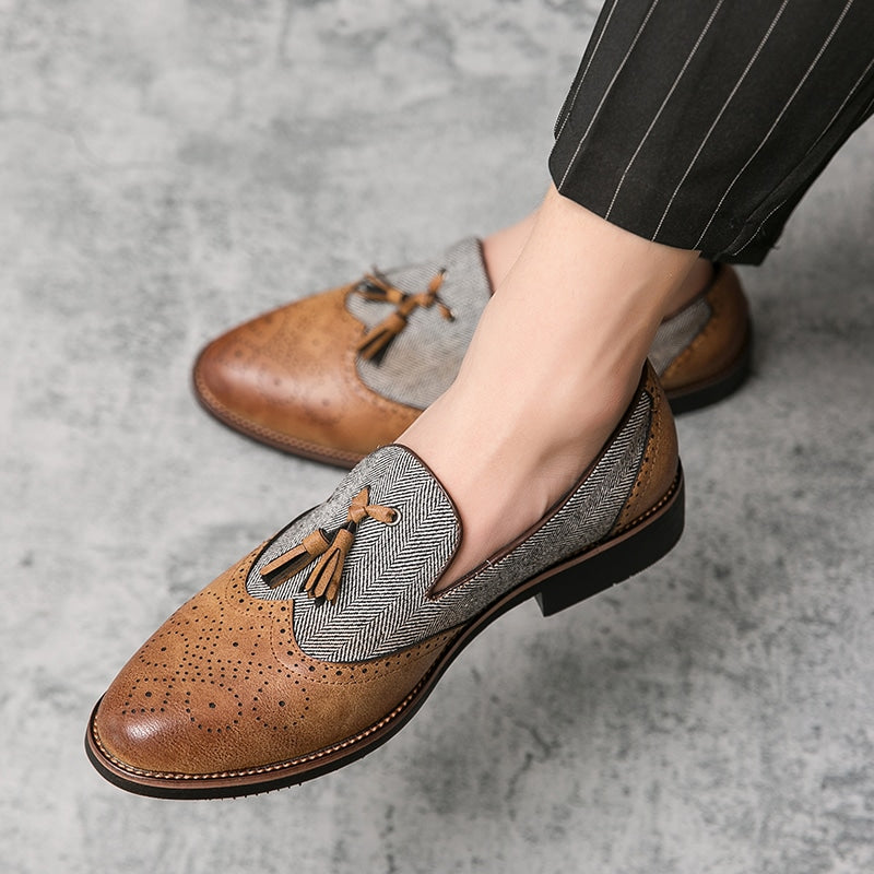Ett par klädda loafers för män i marmorerat brunt syntetläder med sömnadsmönster och grå randig canvas med tofs på ovansidan.