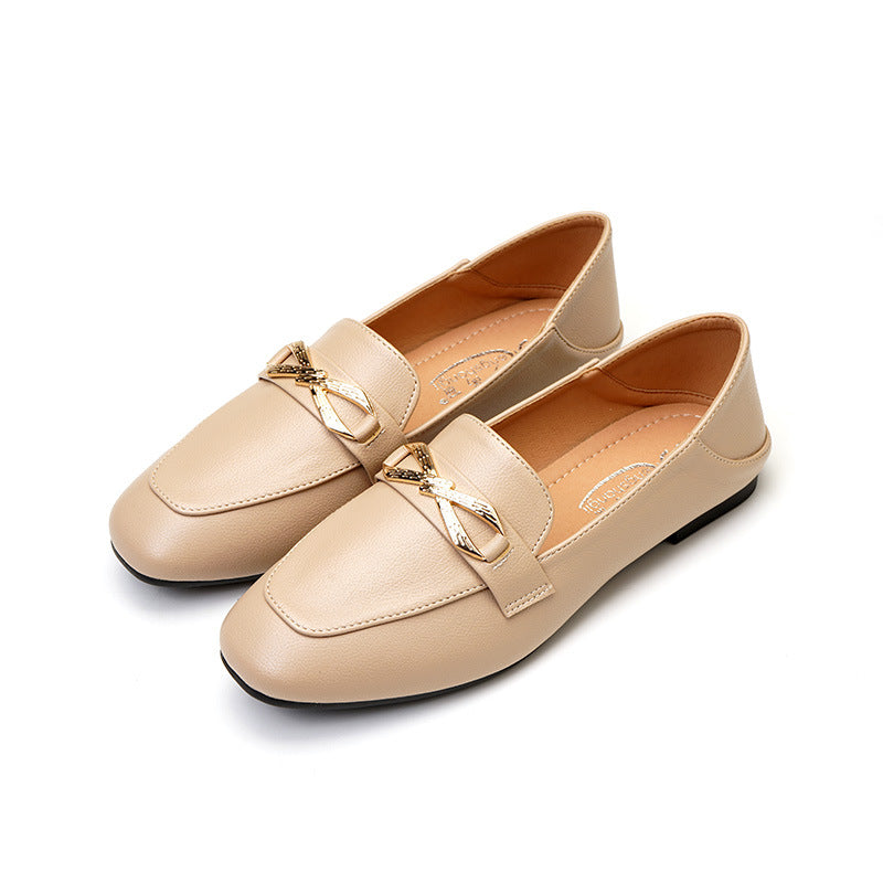 Eleganta läderloafers med guldfärgad rosett för beige kvinnor mot en vit bakgrund