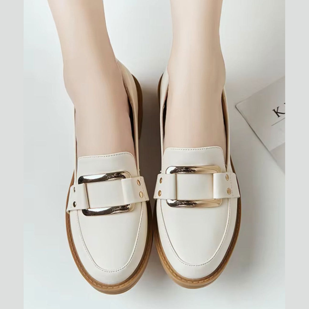 Beige loafers för dam med guldspänne och kamelfärgad sula, på foten