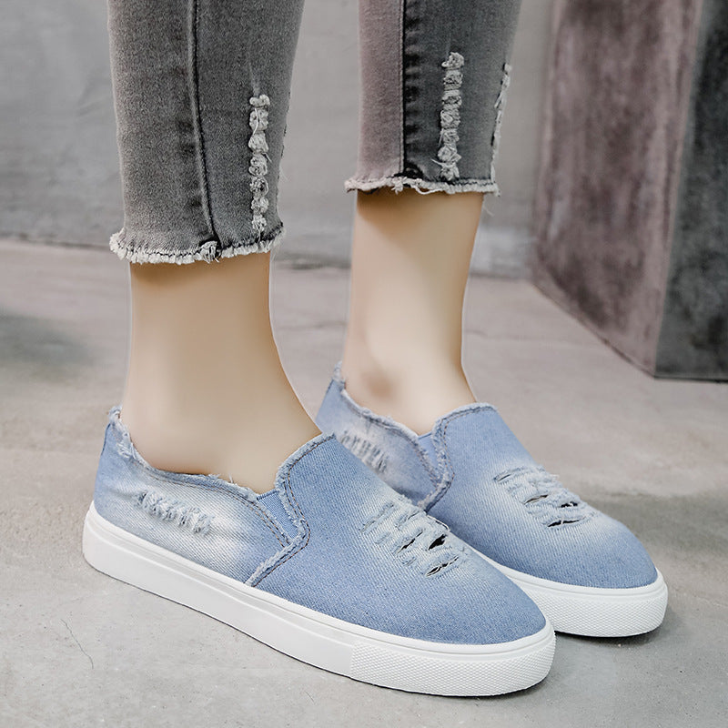 Mockasin i blekt och sliten ljus denim, i profil mot en vit bakgrund