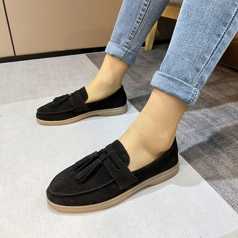 loafer i svart mocka med fransar som bärs av en kvinna