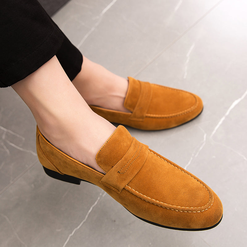 bruna loafers som bärs av en man med korslagda ben och svarta byxor