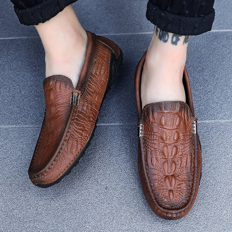 Foto av ett par bruna loafers som bärs av en kvinna med svarta byxor på ett grått golv