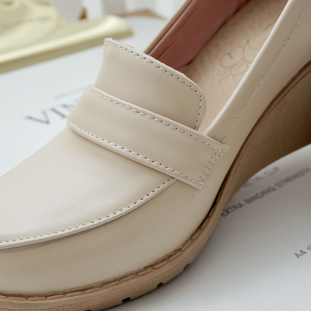 Foto av en beige wedge loafer på en vit tidning
