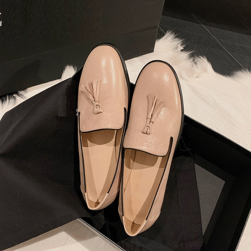 Ett par rosa läderloafers på ett svart element