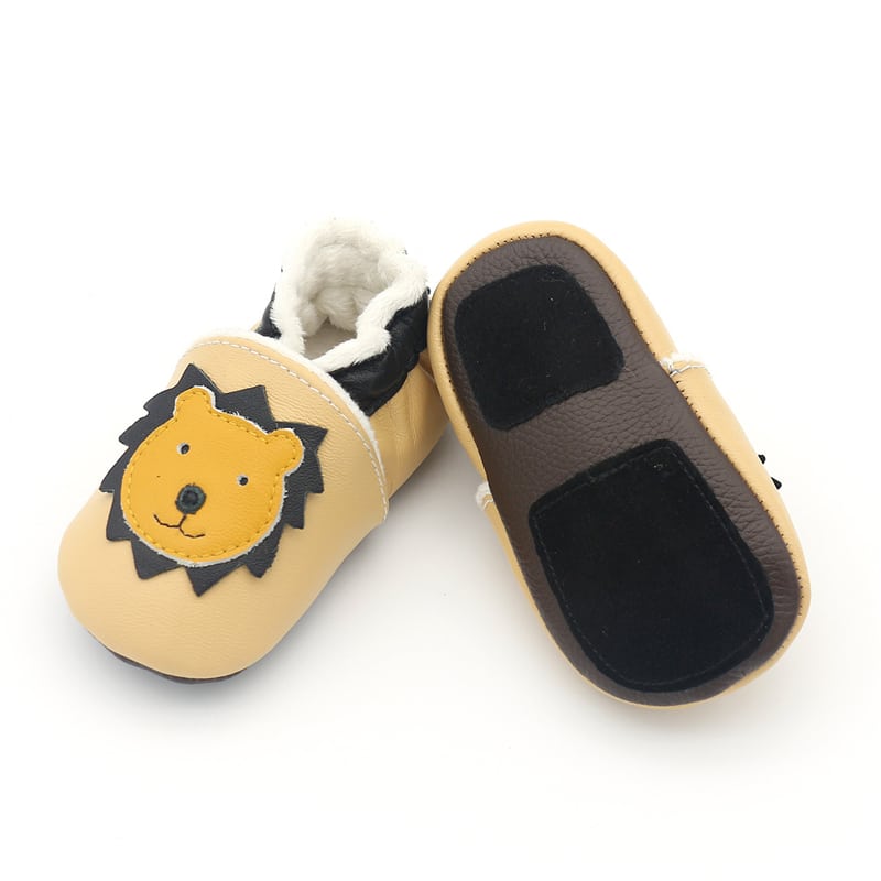 Mjuka babymockasiner i mörkbrunt läder med gult giraffhuvud. Insida av mjuk beige plysch.