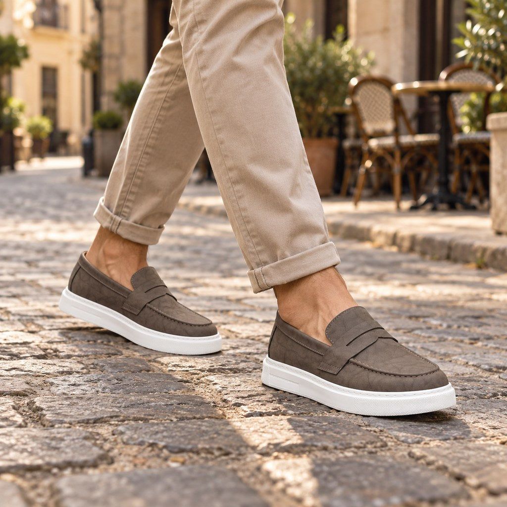 Man i beige chinos med loafers med vit sula på en kullerstensgata