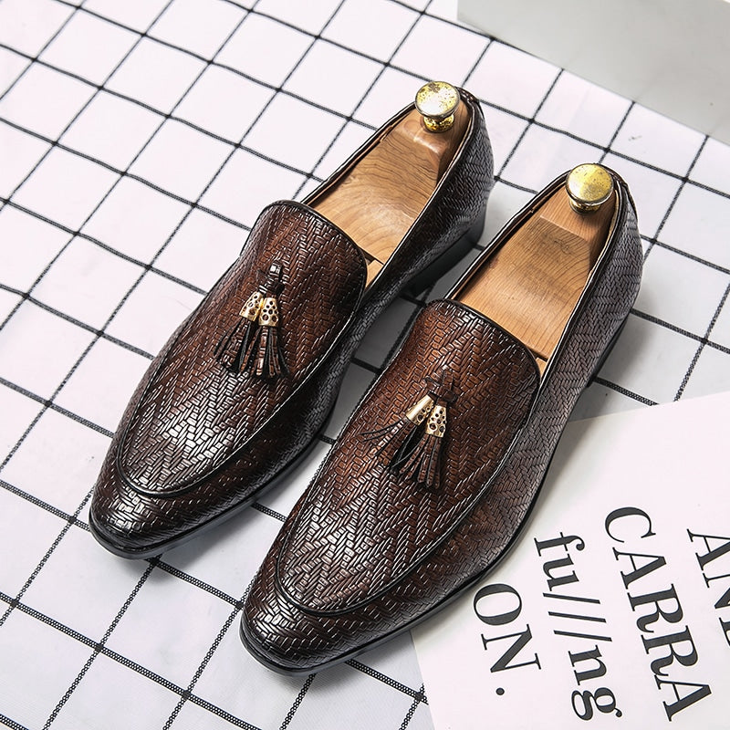 Loafers i läder med sicksackmönster och dekorativa tofsar i läder med ok i guldmetall, mörka spetsiga tår, på vit- och svartrutig botten.
