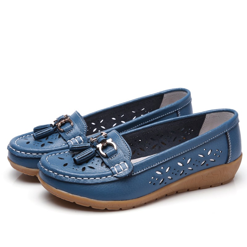 Blå genombrutna loafers mot en vit bakgrund.