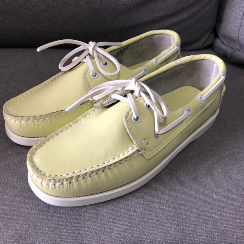 Ett par gula båtloafers med snörning på ett grått golv