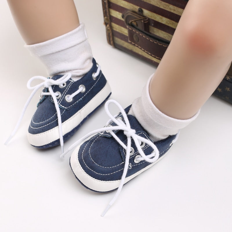 Babyben med vita strumpor och blå mockasiner i båtmodell