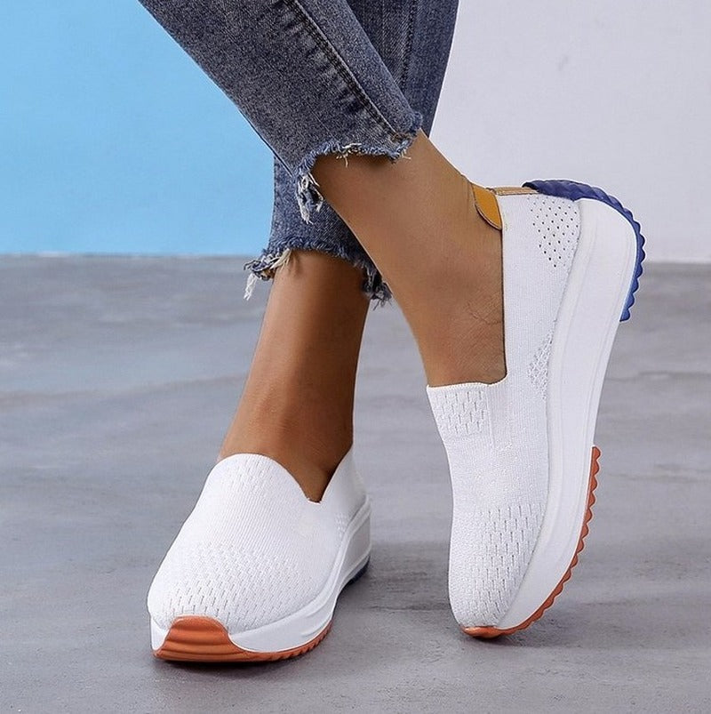 Foto av ortopediska mockaskor av sneaker-typ i vit mesh som andas och har en färgad sula ända ner till hälen.