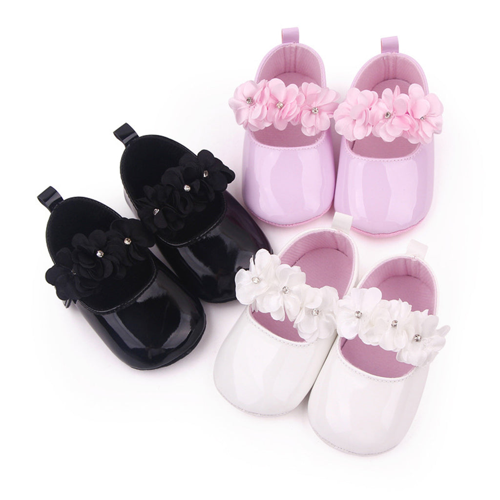Tre par mockasiner med blommor mot vit bakgrund, i svart, rosa och vitt