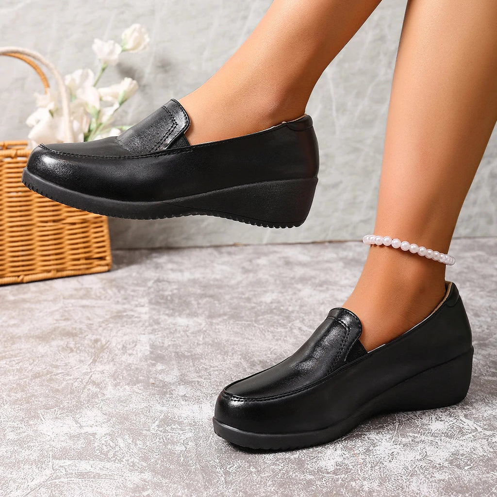 Svarta loafers för dam med kilsula sedda bakifrån