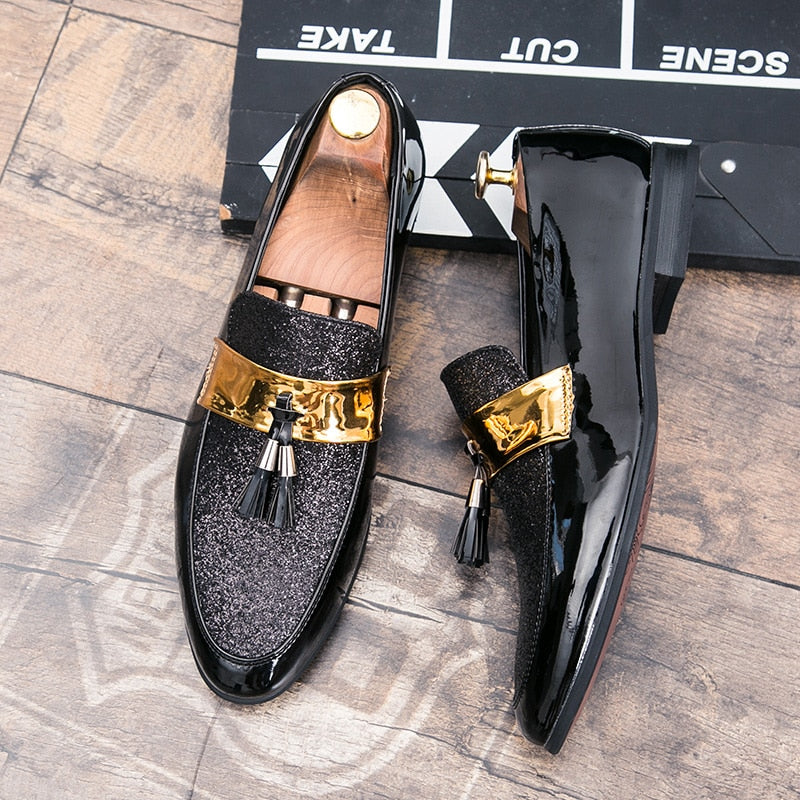 Svarta loafers med guldband på ovansidan och en tofs hängande från undersidan