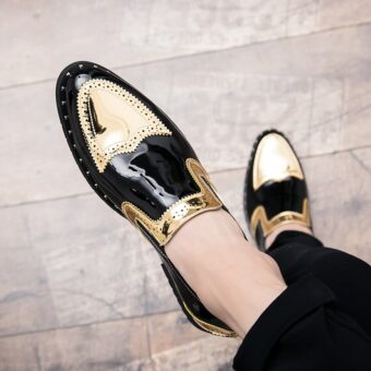 Korsade fötter i svarta och guldfärgade loafers på parkettgolv