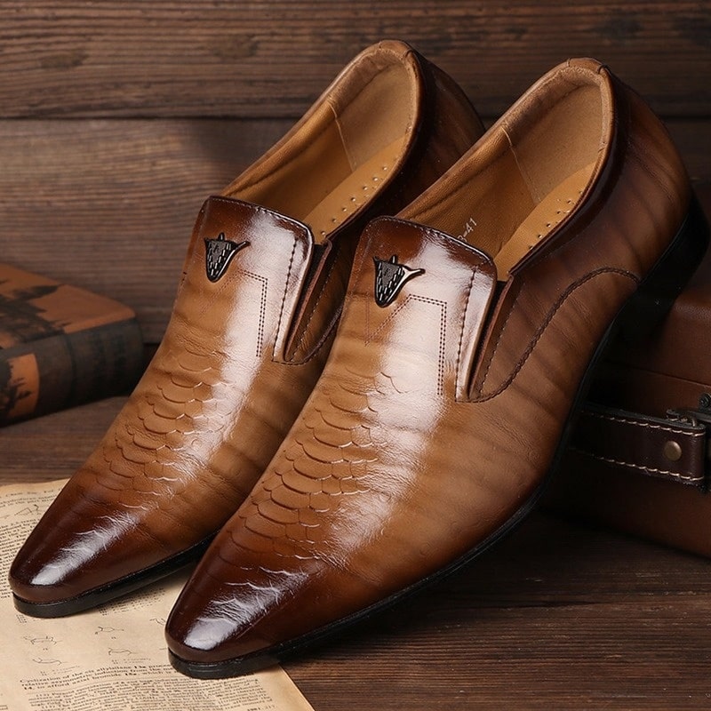Ett par bruna mockasiner med gradient effekt och ormskinn med en logotyp på ovansidan av skon