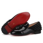 Svarta loafers i lack med spikar baktill på skon.