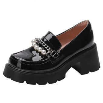 En svart loafer i lackskinn med tjock svart sula och häl dekorerad med en silverkedja och vita pärlor på ovansidan av skon, insidan är puderrosa mot en enfärgad vit bakgrund.