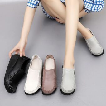 Ben av en kvinna med grå skor på fötterna och andra skor bredvid henne, svart, vitt och brunt