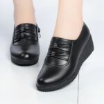 Bekväma svarta wedge loafers med lädereffekt för kvinnor mot en vit bakgrund