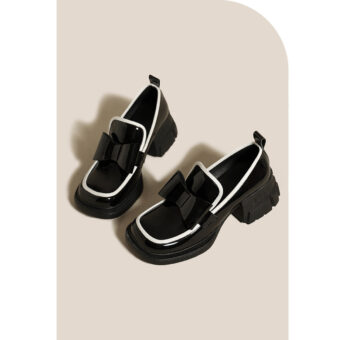 Platform loafers prydda med en förtjusande svart fluga för kvinnor med beige bakgrund