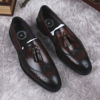 Tassel loafers i brunt äkta läder för män med grå bakgrund