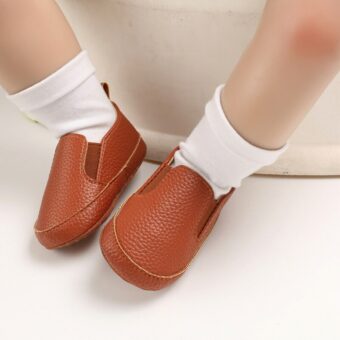 Baby med vita strumpor och vanliga bruna mockaskor i syntetiskt läder