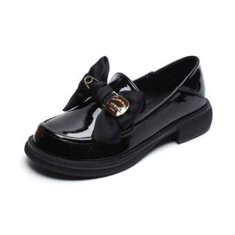 Svarta loafers i brittisk stil med fluga för kvinnor mot en vit bakgrund