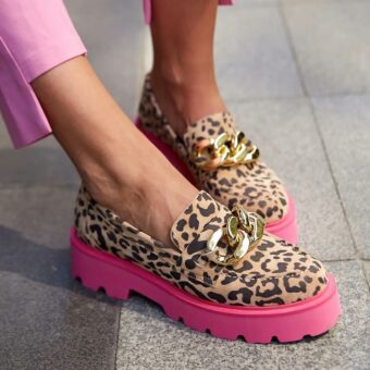Fot av en kvinna med rosa byxor och leopardfärgade loafers med rosa sula