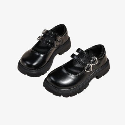 Paire de mocassins noirs avec double bride et un détail coeur dessus, sur fond gris.